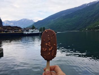 Close-up of hand holding ice cream on lake