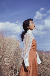 Woman standing on field against sky