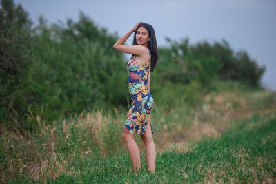 Full length of woman with arms raised on field