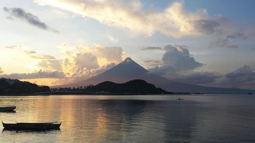 Boat in river against mountains and cloudy sky during sunset