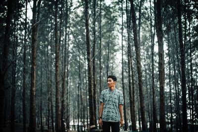 Man standing against trees in forest