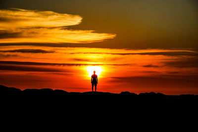 Silhouette man standing against orange sky