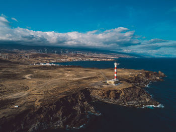 Lighthouse by sea against sky