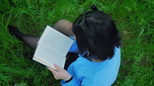Rear view of woman reading book on field