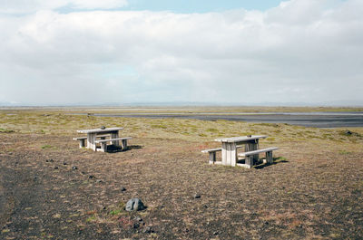 Picnic tables on field against sky