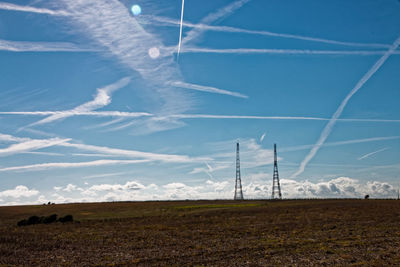 Low angle view of wind turbines on field against blue sky