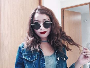 Portrait of young woman wearing sunglasses while standing at home