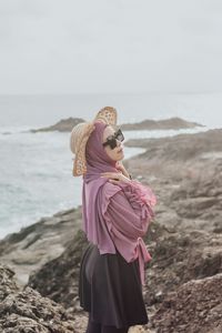 Woman standing at beach against sky