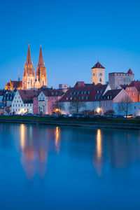 Illuminated buildings against blue sky at dusk