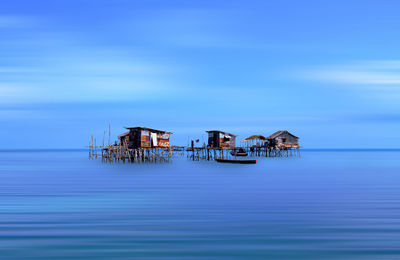 Stilt houses in sea against sky
