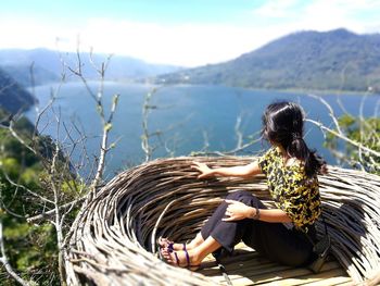 Woman looking at lake while sitting on observation point