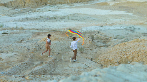 Children with a kite walk on dry white clay quarry.