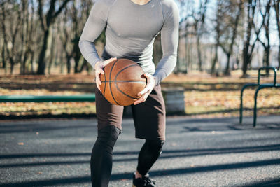 Midsection of man playing basket ball on sunny day