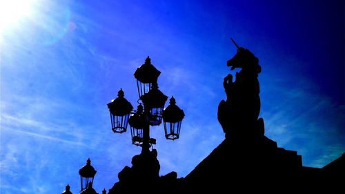 Low angle view of silhouette statue against blue sky