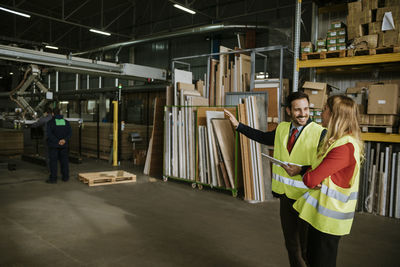 Smiling man and woman wearing reflective vests in warehouse