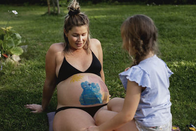 Mother with daughter sitting on lawn