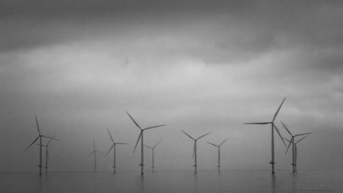 Wind turbines in sea against sky