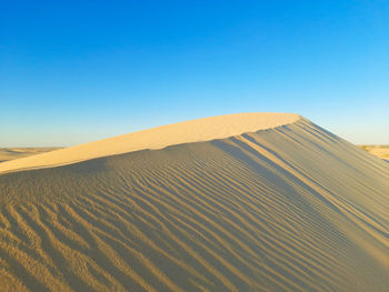 Scenic view of desert against clear blue sky