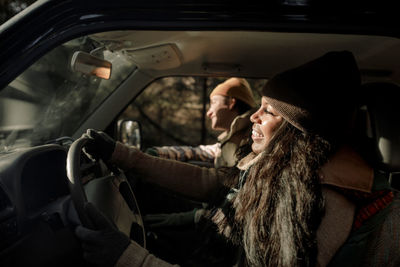 Smiling young women driving off-road vehicle with male friend