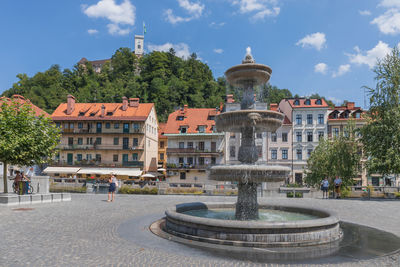 Fountain in city against sky