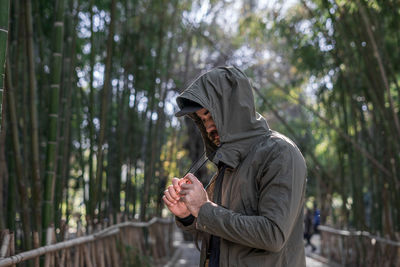 Portrait of a man adjusting his jacket's hood in a bamboo park in morocco