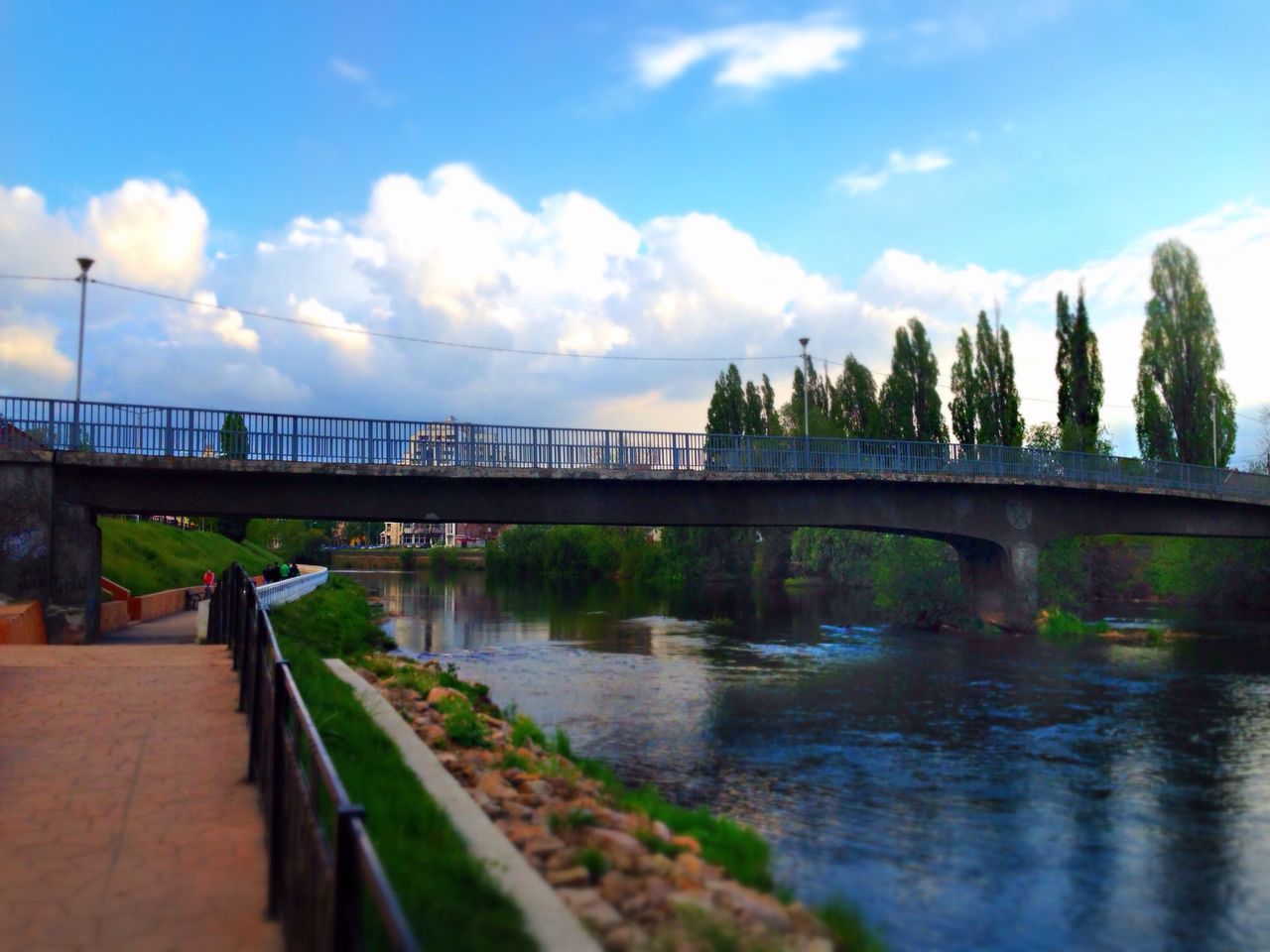 water, bridge - man made structure, connection, sky, built structure, architecture, river, cloud - sky, railing, bridge, tree, cloud, reflection, footbridge, nature, tranquility, outdoors, sunlight, day, scenics