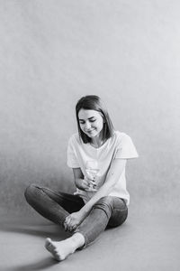 Portrait of a young woman sitting against wall