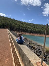 People sitting on shore against sky