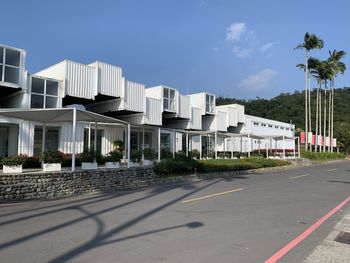 Road by buildings in city against sky