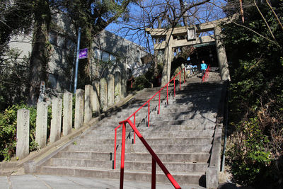 People on staircase by fence against trees