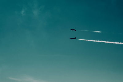 Low angle view of airshow in blue sky