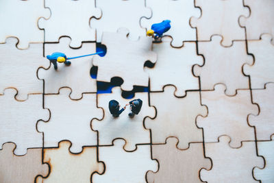 High angle view of figurines on wooden jigsaw puzzle