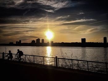 Silhouette of people in river at sunset