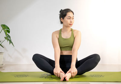 Women do yoga on the green yoga mat for meditating and exercising in the home.