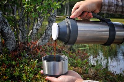 Cropped woman pouring coffee from insulated drink bottle