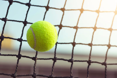 Close-up of tennis ball against net