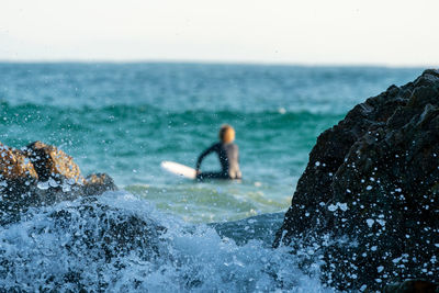 People on rocks by sea against sky