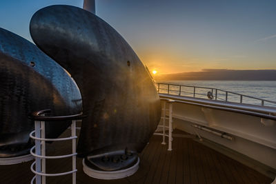 Close-up of railing against sea during sunset