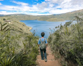 Rear view of man standing on mountain against sky