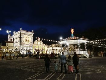 Group of people in front of illuminated building at night