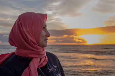 Close-up of man standing against sea during sunset