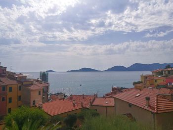 Houses in town by sea against sky