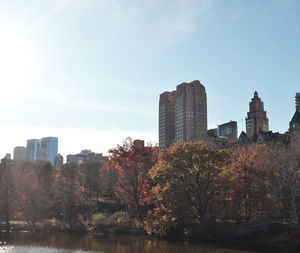 Buildings by lake against sky during autumn