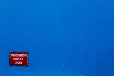 Low angle view of warning sign against blue sky