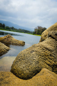 View of calm beach against cloudy sky