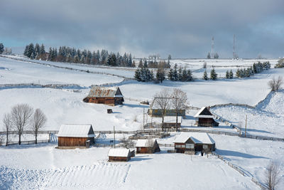 Houses on snow covered land against sky