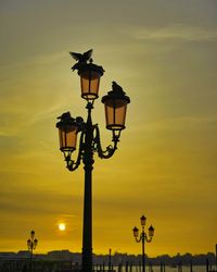 Low angle view of street light against orange sky