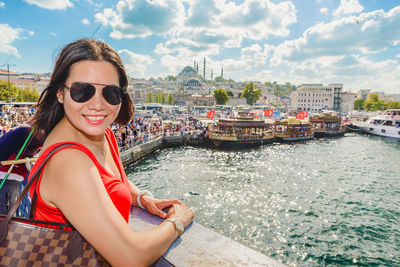 Portrait of smiling young woman in boat against sky