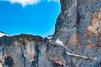 Low angle view of rocky mountains against blue sky