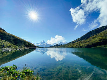 Scenic view of lake and mountains against sky with sun